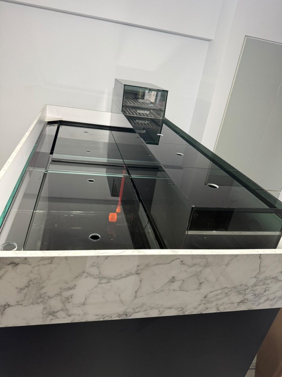 Braced glass top on a marble-finish cabinet, up close.